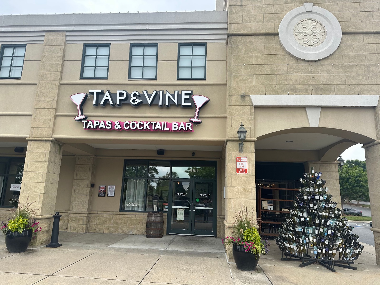 PHOTO-2025-07-01-10-22-37 Full façade of Tap & Vine Tapas & Cocktail Bar in Ballantyne with dual entranceways, wine decor, and tall tower detail.